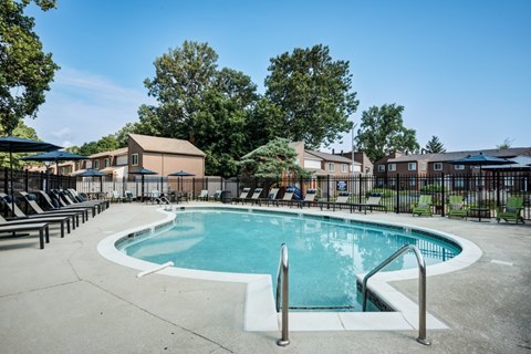 A round swimming pool surrounded by a concrete floor and metal railings.