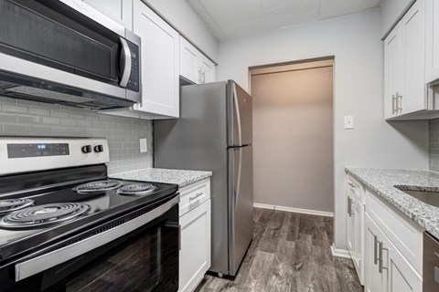 A kitchen with a black stove top oven and a stainless steel refrigerator.