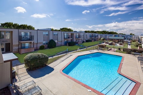 A swimming pool in a sunny day surrounded by a fence.