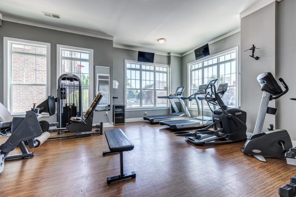 A spacious gym with a variety of equipment including treadmills, stationary bikes, and weight machines.