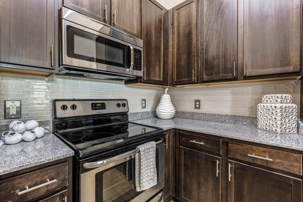 A kitchen with a black stove and wooden cabinets.