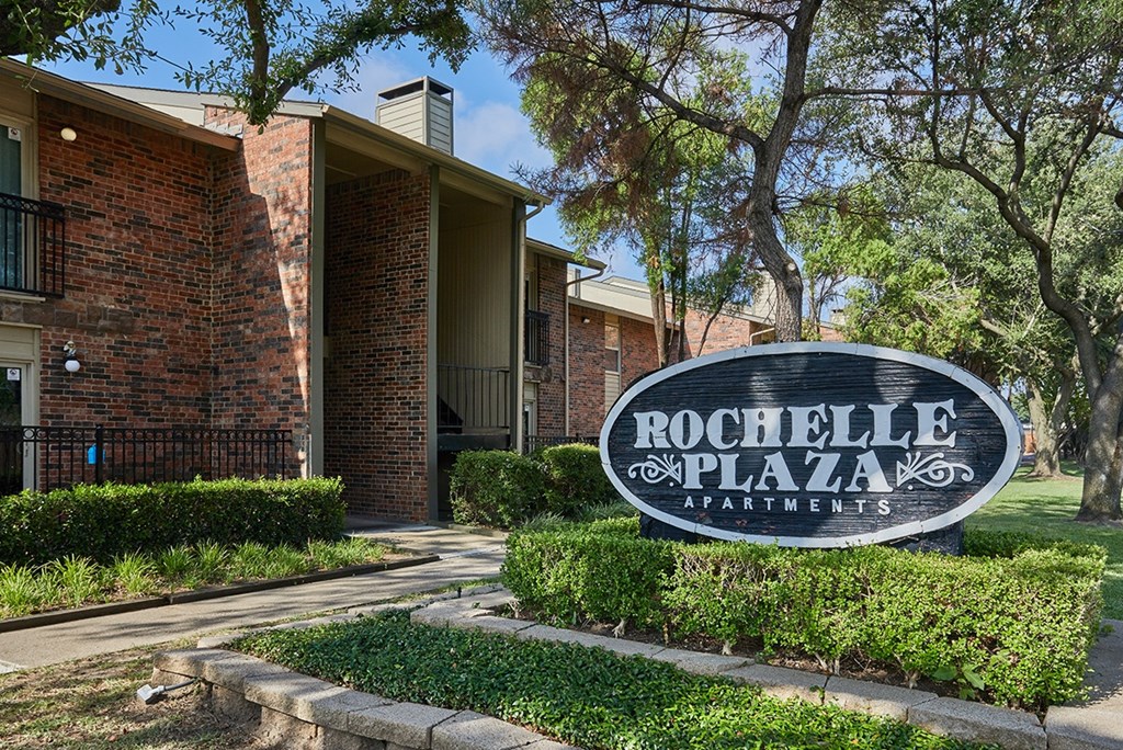 A sign that says Rochelle Plaza Apartments in front of a building.