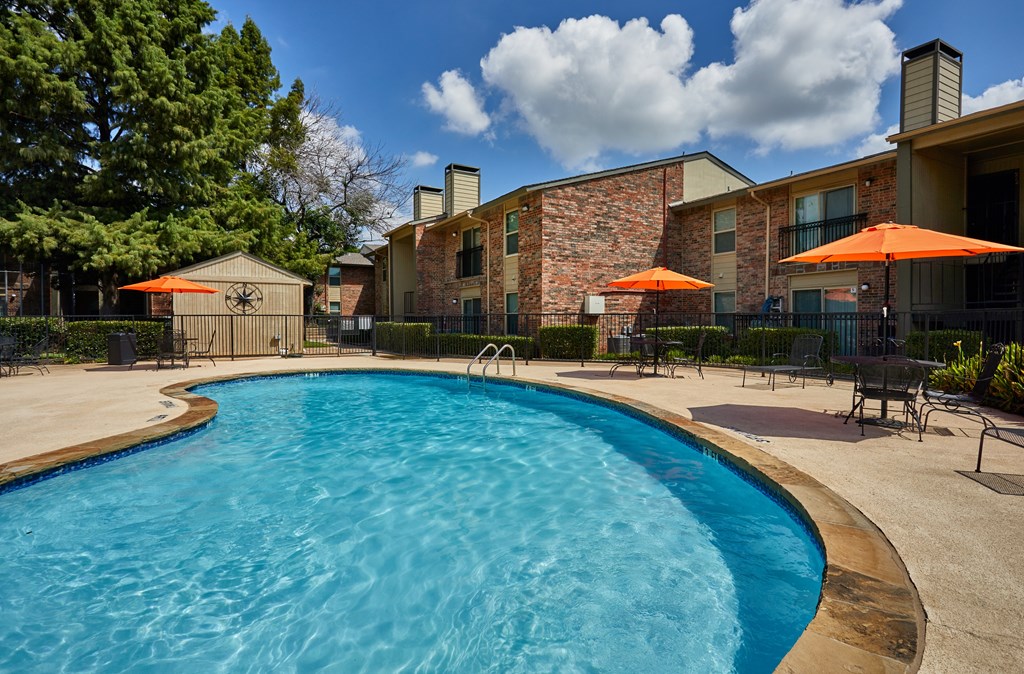 A swimming pool surrounded by a fence and umbrellas.