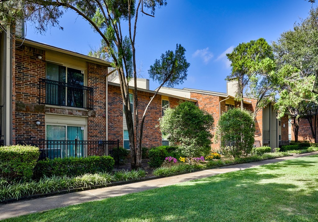 A row of houses with green lawns and trees.