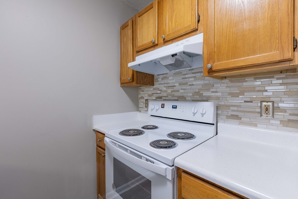 an empty kitchen with a stove and oven and wooden cabinets