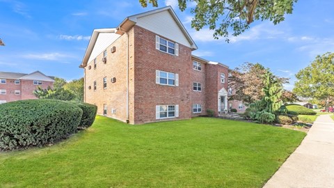 A red brick building with a green lawn in front.