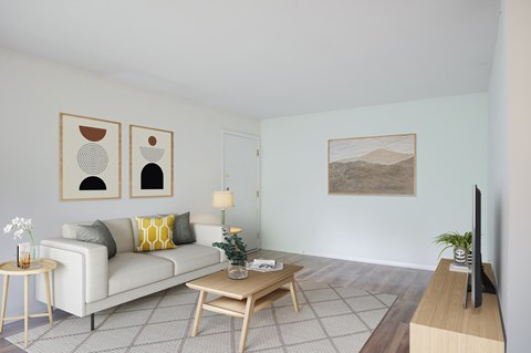 A living room with a white couch, a coffee table, and a painting on the wall.