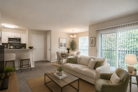 A living room with a white couch, a coffee table, and a dining area with a table and chairs.