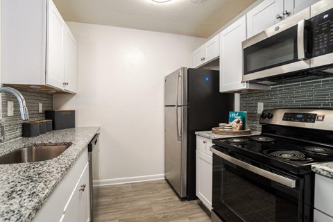 A kitchen with black appliances and white cabinets.