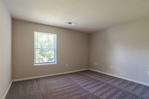 A room with a window and carpeted floor.