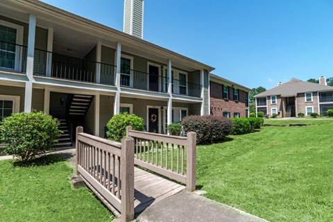 A wooden fence leads to a building with a balcony.