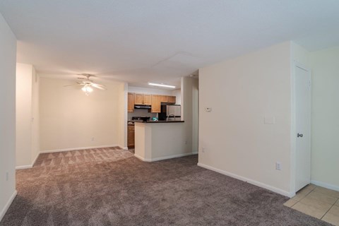 A spacious living room with a carpeted floor and a ceiling fan.