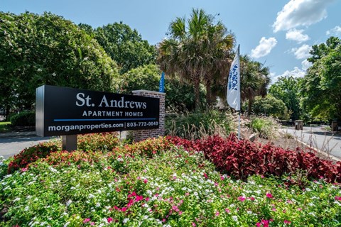 A sign for St. Andrews Apartment Homes is surrounded by flowers.