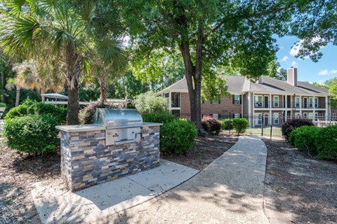 A brick mailbox sits on a sidewalk in front of a house.