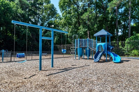 A playground with a blue swing set and slide.
