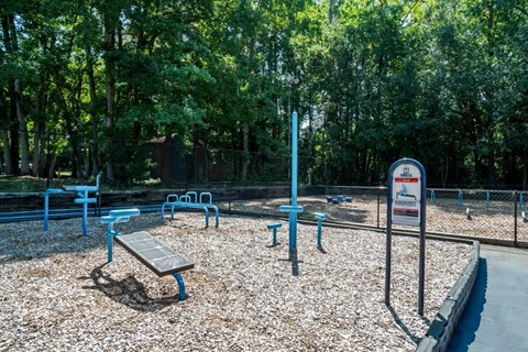 A playground with a sign and blue benches.