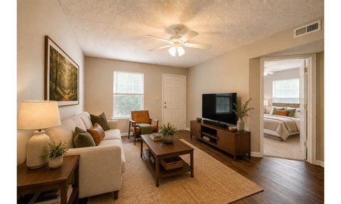 A living room with a couch, a chair, a coffee table, and a television.