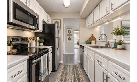 A kitchen with black appliances and white cabinets.