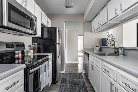 A kitchen with black appliances and white cabinets.