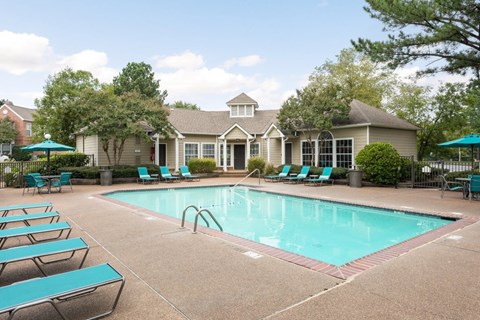 A large swimming pool surrounded by lounge chairs and umbrellas.