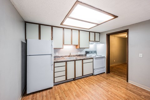 A kitchen with a refrigerator, sink, and cabinets.