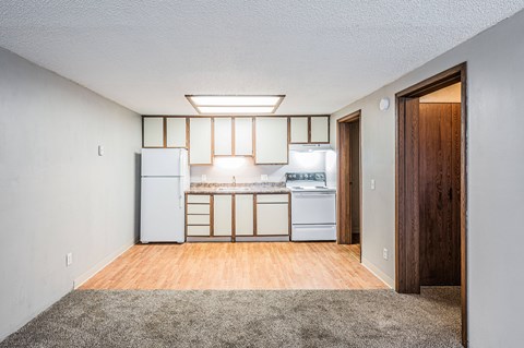 A kitchen with white appliances and wooden floors.