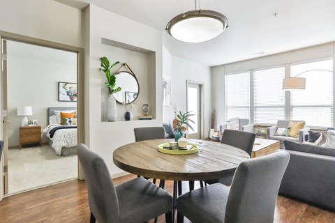 A modern dining room with a round table and grey chairs.