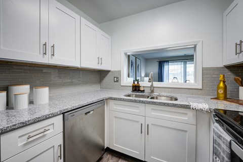 A kitchen with white cabinets and a stainless steel dishwasher.