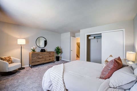 A bedroom with a large bed and a chair.
