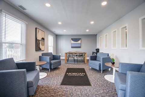 A waiting room with chairs and a table with a sign that says "MORGAN" on the carpet.