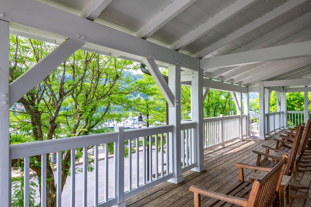 a covered porch with wooden chairs and a view of a body of water
