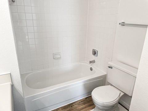 A white bathroom with a toilet, tub, and shower.