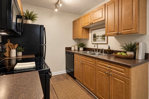 A kitchen with black appliances and wooden cabinets.