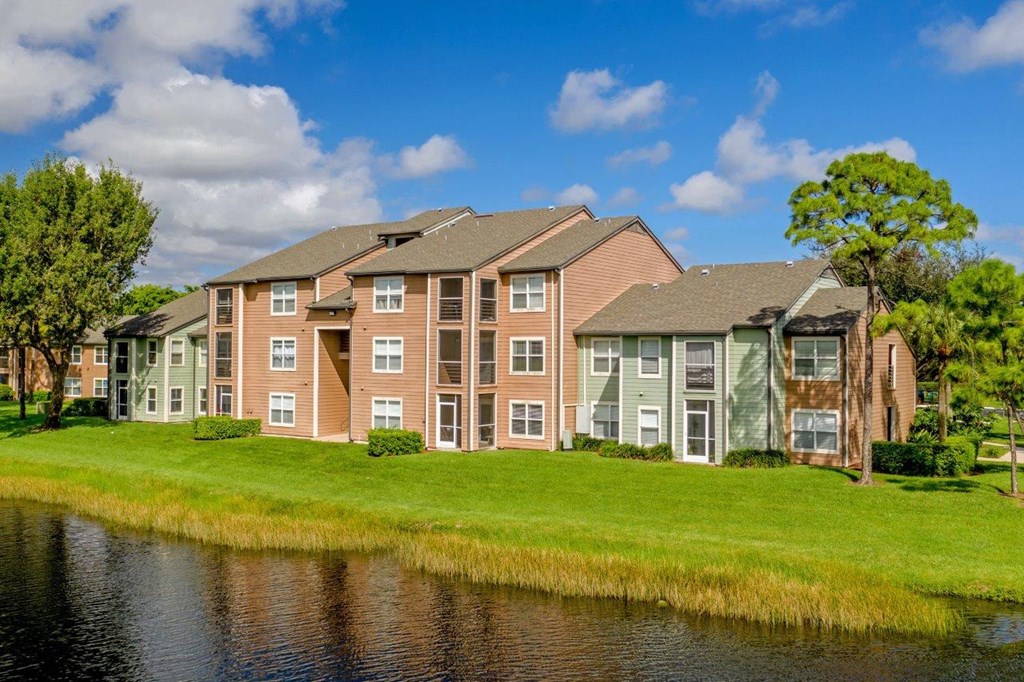A large apartment complex with a pond in front.