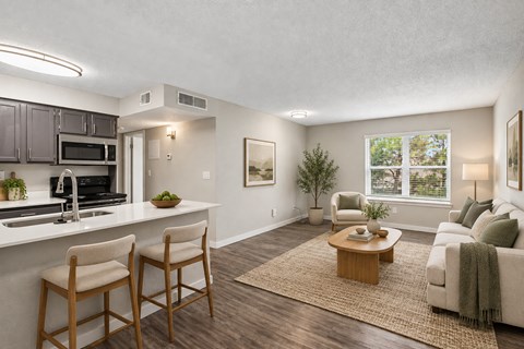 A well-lit living room with a kitchen area in the background.