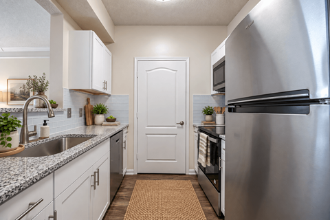 A modern kitchen with a stainless steel refrigerator and white cabinets.