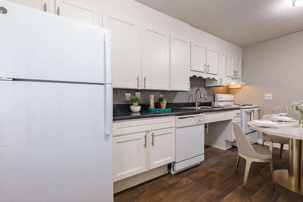 a kitchen with white cabinets and a white refrigerator and a table and chairs