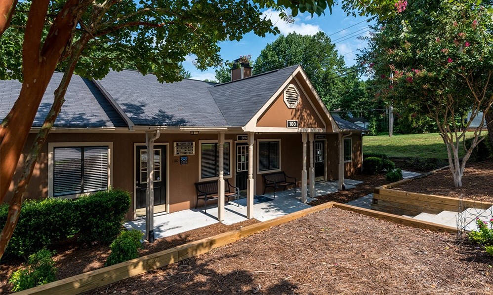 the front of a house with a porch and a gravel driveway