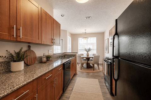 A kitchen with a black refrigerator and wooden cabinets.
