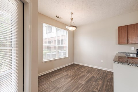 A kitchen with wooden floors and a window with blinds.