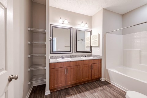 A bathroom with a sink, mirror, and wooden cabinets.