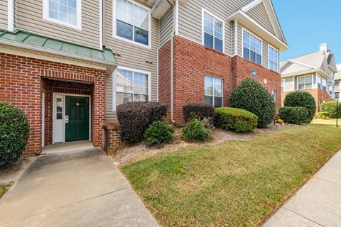 A residential building with a green door and a well-maintained lawn.