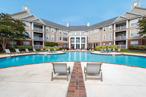 Two lounge chairs sit on the ground in front of a pool.