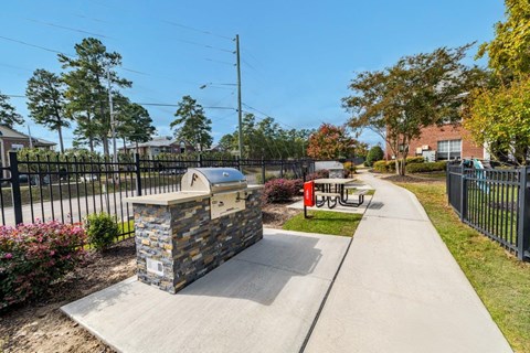 A stone structure with a black fence and a bench with a red sign on it.