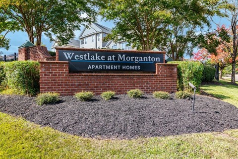 A sign for Westlake at Morganton Apartment Homes is in front of a house.