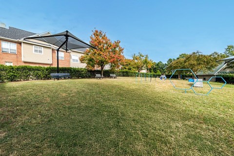 A grassy area with a playground and apartment buildings in the background.
