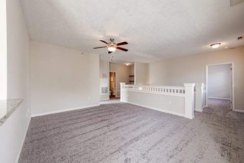 A spacious room with a ceiling fan and carpeted floor.