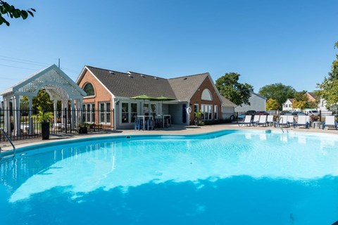 A large swimming pool in front of a building with a poolside lounge.