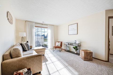 A living room with a couch, chair, and a small table with a plant on it.