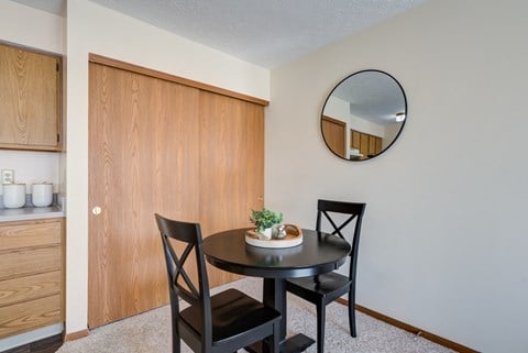 a dining area with a table and two chairs and a mirror